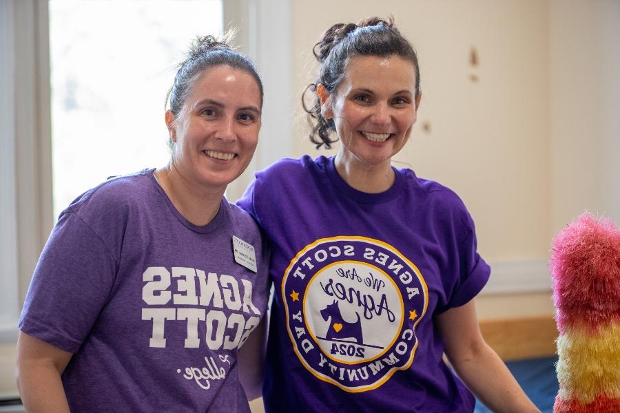 two people pose for a photo wearing purple shirts